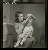 583 Sickan Carlsson för 25an Allers. Sickan Carlsson sitter och kammar en liten flicka.