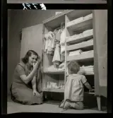 583 Sickan Carlsson för 25an Allers. Sickan Carlsson sitter på golvet framför en barngarderob med en liten flicka.