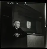 584 Brunsviks Folkhögskola. En man föreläser från en talarstol.