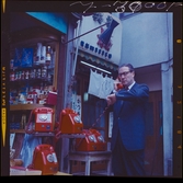 585/8 Facit Tokyo Daberg. En man telefonerar vid en station med flera röda telefonapparater.