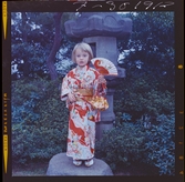 585/8 Facit Tokyo Daberg. Ett barn i kimono står i en trädgård.