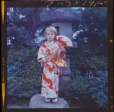 585/8 Facit Tokyo Daberg. Ett barn i kimono står i en trädgård.