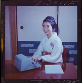 585/8 Facit Tokyo Daberg. Porträtt av en kvinna i kimono som arbetar vid en Facit maskin.