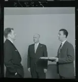 585/8 Facit Tokyo Daberg. Tre män, en överlämnar en inslagen gåva till en annan.