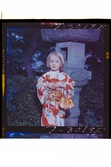 585/8 Facit Tokyo Daberg. Porträtt av ett barn i kimono som står i en trädgård.