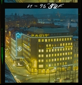 585/40 Facit Nattbild från N.K + Södra Kungstornet. Kvällsbild. Facit-skylt på taket av fastigheten Styrpinnen 22, ritad av arkitekt Ivar Tengbom i hörnet Hamngatan / Kungsträdgårdsgatan i Stockholm.