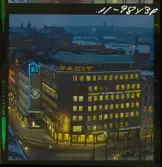 585/40 Facit Nattbild från N.K + Södra Kungstornet. Kvällsbild. Facit-skylt på taket av fastigheten Styrpinnen 22, ritad av arkitekt Ivar Tengbom i hörnet Hamngatan / Kungsträdgårdsgatan i Stockholm.