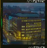 585/40 Facit Nattbild från N.K + Södra Kungstornet. Kvällsbild. Facit-skylt på taket av fastigheten Styrpinnen 22, ritad av arkitekt Ivar Tengbom i hörnet Hamngatan / Kungsträdgårdsgatan i Stockholm.