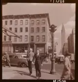 1690 New York, allmänt. Gatubild. Ett par män har just passerat ett övergångsställe. Chrysler building syns i bakgrunden.