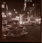 1690 New York, allmänt. Gatubild nattetid. Neonljus, reklam, bil parkerad i förgrunden.
