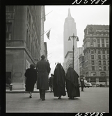 1690 New York allmänt (N.Y. Herald Tribune). Nunnor passerar på trottoaren, Empire state building.