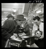 1690 New York allmänt (N.Y. Herald Tribune). K W Gullers blir visad en kamera av en expedit i butik.