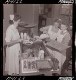 1711 En sjuksköterskas arbetsdag. Mat portioneras ut från en vagn.