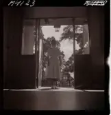 1711 En sjuksköterskas arbetsdag. En sköterska står i dörröppningen till en altan/ balkong.