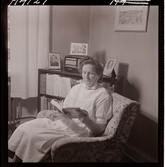 1711 En sjuksköterskas arbetsdag. En sköterska sitter och läser i en fåtölj.