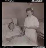 1711 En sjuksköterskas arbetsdag. En sköterska undersöker en patient i säng.