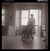 1711 En sjuksköterskas arbetsdag. En sköterska kör en patient i rullstol.