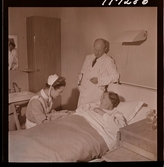 1714 En sjuksköterskas arbetsdag på södersjukhuset. En sköterska och en läkare vid en patients säng.
