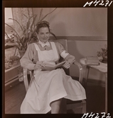 1714 En sjuksköterskas arbetsdag på södersjukhuset. Porträtt av en sköterska som sitter och läser i en bok.