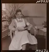 1714 En sjuksköterskas arbetsdag på södersjukhuset. Porträtt av en sköterska som sitter och läser i en bok.