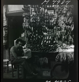 1717/K Istanbul allmänt. En man sitter framför butik som säljer skor/ tofflor.