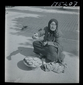 1717/K Istanbul allmänt. Gatuförsäljare. En äldre kvinna sitte rpå trottoaren och säljer något/ nötter?