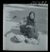 1717/K Istanbul allmänt. Gatuförsäljare. En äldre kvinna sitte rpå trottoaren och säljer något/ nötter?