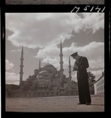 1717/L Istanbul allmänt. En turistande man i uniform fotograferar med sin kamera framför en moské.