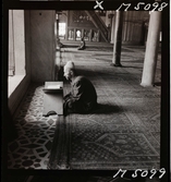 1717/L Istanbul allmänt. En man sitter i en moské och läser koranen.