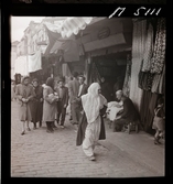 1717/L Istanbul allmänt. Folkliv på gata. En butik säljer tyger/ textil.