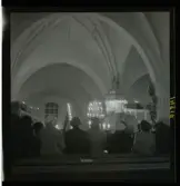1950. Leksands kyrka. Folk stående i kyrkbänkar