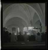 1950. Leksands kyrka. Folk stående i kyrkbänkar