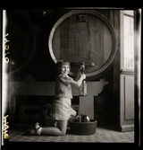 1950. Frankrike. flicka tappar ut vin från en tunna