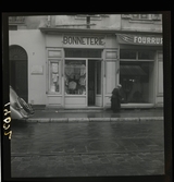 1950. Frankrike. En kvinna gående förbi en trikåbutik