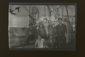 Sju besättningsmän poserar på ett fartyg.