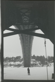En man står på isen under en bro som håller på att byggas.