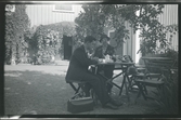 En man och en kvinna sitter vid ett bord i en trädgård och dricker kaffe.