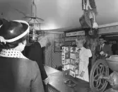 Interiör av Wadköpings diversehandel, Wadköpings handelsbod i Tenngjutaregården, kulturreservatet Wadköping. 
Konungen besöker handelsboden vid invigningen 4 juni 1965. Med stort intresse tar konungen del av vad amanuens Eva Alström har att berätta om den gamla handelsboden.