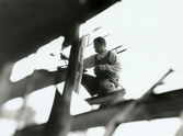 Nya Teaterhuset byggs upp 1997 - 1998. Närbild på en person som är tagen snett framifrån. Personen står utomhus på en byggnadsställning och arbetar med huset.