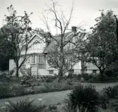 En bostad med fritrappa, frontespis, mansardtak och glasveranda.