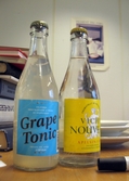 Två dricksflaskor på ett bord. Den ena Grape Tonic, den andra Vichy Nouveau. Interiörfotografi från byggnad vid Soabs industrianläggning i Mölndals Kvarnby, år 2007. Anläggningen användes vid fototillfället av Hexion Speciality Chemicals Sweden AB.