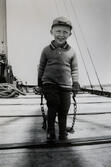 Lennart Blomdin på sin far Edwins pråm, släpande på kedjor i tidig ålder. Lennart drev under lång tid sin omtyckta verkstad på Björkö. Bilden är tagen ca 1943.