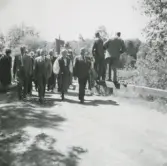 En samlad grupp, från SLU eller Bondeförbundet, går på en grusväg, Backen eller Högen okänt årtal. Någon håller en fana i luften.