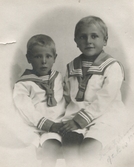 Ateljéfoto av bröderna Gustav (1916 - 2006) och Albert Eklund (1913 - 2005) cirka 1920. Pojkarna är klädda i sjömanskläder. Söner till Gustava och Carl Eklund, Sagereds gård 3:2.