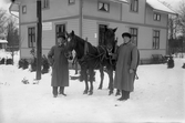 Män med hästar framför huset