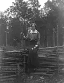 Kvinna sittande på gärdesgård