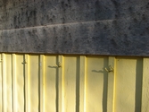 Krokar för att hänga upp kläder, vilka sitter på en gulmålad yttervägg, Hällesåkers dansbana år 2010. 
Relaterade motiv: 2024_1119 - 1137.