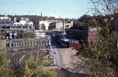 Kvarnbygatan österut 1970-tal. I förgrunden ses takåsar till byggnader vid Gamla Torget samt Götiska Förbundets friskola. Till vänster ses Soabs industriområde. Rakt fram, uppifrån, ses 