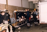 Mölndals brandstation i Trädgården, Mölndal, på 1980-talet. Fyra brandmän tar på sina arbetskläder vid utryckning.