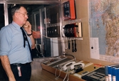 Mölndals brandstation i Trädgården, Mölndal, på 1980-talet. En brandman står och telefonerar i larmcentralen.